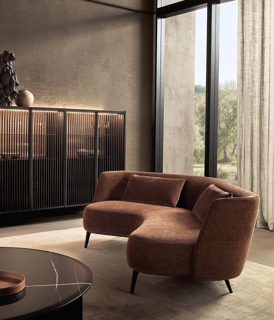 Sunday sofa with removable cover in Yukon 27 tabacco fabric and matt brown nickel feet. Sunday armchair with removable cover in Siro 02 lino fabric and matt brown nickel feet. Code day system with Tape strip doors in black elm and clear glass, handle in matt slate. Internal structure in black elm with backrest in grey linen fabric, integrated LED light. Top in black elm. Carpet Shindo natural.
