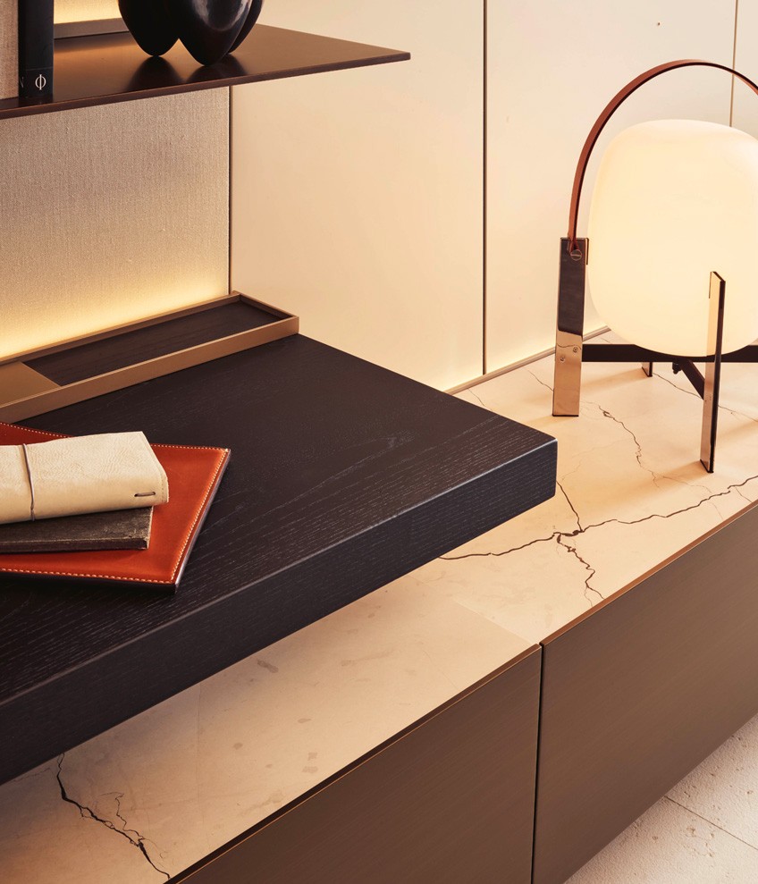 Detail of Code wall-mounted backlit shelf with garnet matt lacquer finish. Cable channel with matt slate finish, equipped with inductive charging device for smartphones.