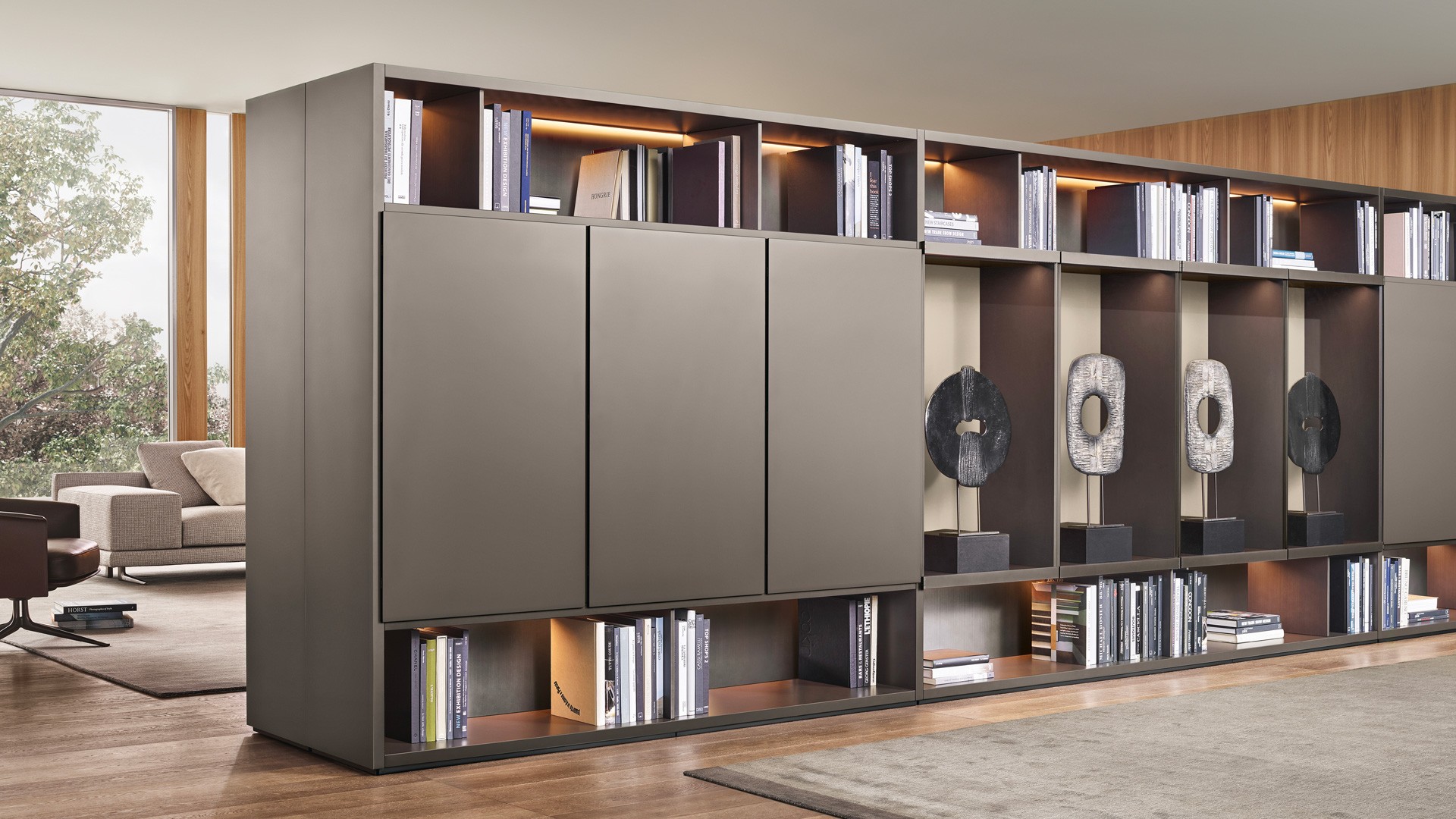 Система корпусных модулей Wall System: структура и распашные двери Slim с лакированной матовой отделкой цвета визоне. Стенки и боковые панели с лакированной металлической отделкой титанового цвета. Витрины Ghost с дверями из прозрачного просветленного стекла и окрашенным профилем с матовой отделкой цвета ардезия. Стенки с лакированной глянцевой отделкой цвета канапа. Встроенная светодиодная подсветка. Ковер Plain цвета тортора.