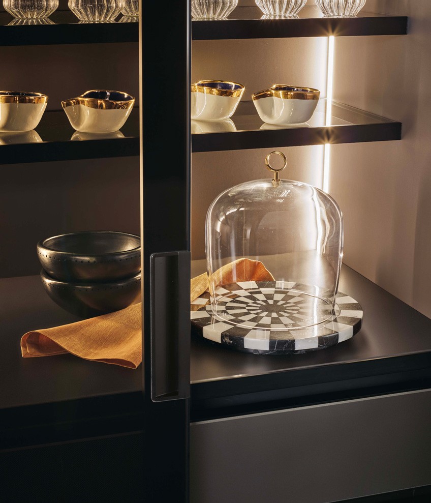 Detail of the glass door PR22 with integrated handle, chests of drawers in laminate touch nero, glass shelves with black anodized aluminium frame and integrated led lighting.