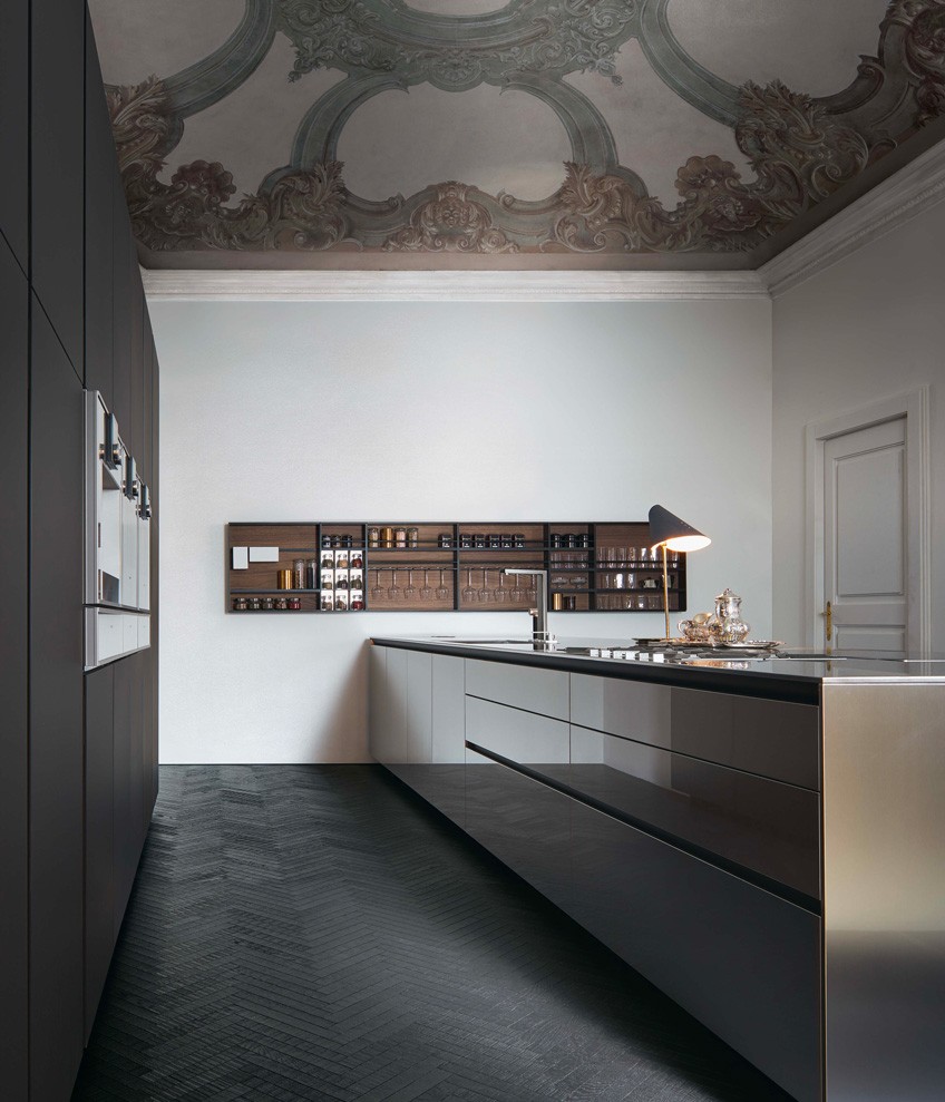 Base units with doors, drawers and pull-out storage baskets in scotch brite steel, top in scotch brite steel Barazza with carbone embossed lacquered aluminium support frame. Shaker with back panels in walnut c., shelves in moka anodized aluminium and bars in embossed lacquered moka.