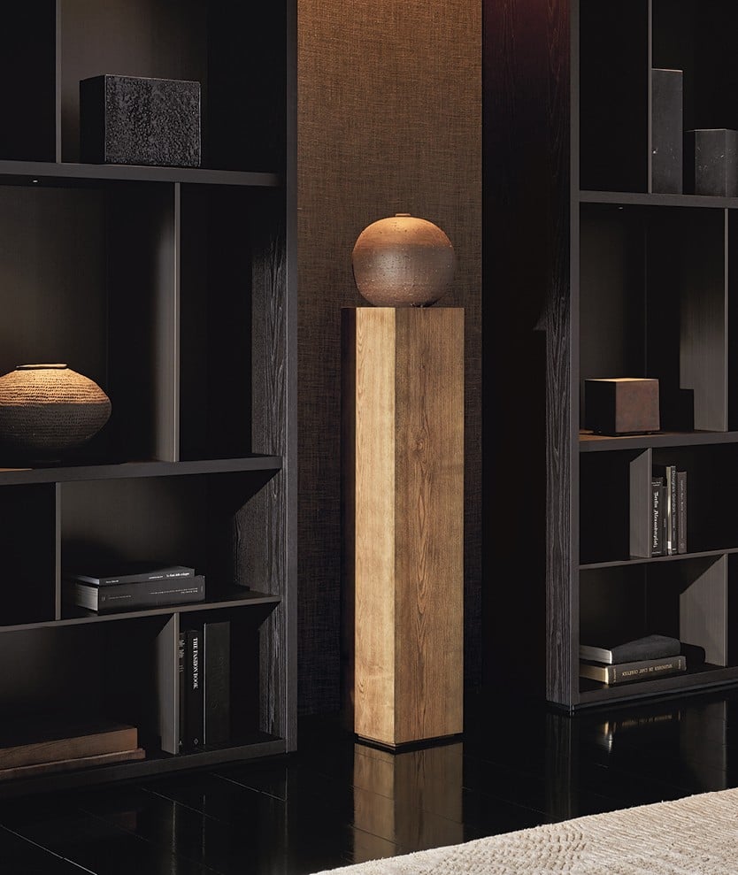Surface wall panelling in fabric Mesh bronzo with mat ardesia profiles. Wall System composition with structure and recessed shelves in black elm, grids and backs in metal lacquer bronzo, compartments with Stage backs in fabric Mesh moka, integrated led light. Carpet Trace white.
