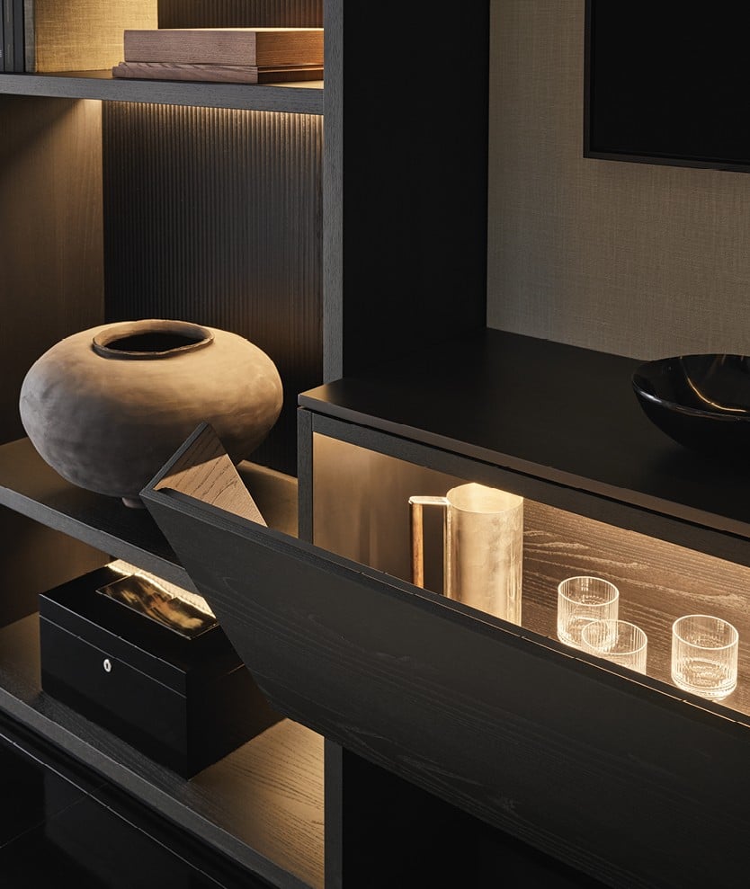 Wall System with structure and recessed shelves in black elm, backs in black elm print, central compartment with Stage backs in fabric Mesh ecru and Block element with flap doors at the sides and two drawers in black elm, top in metal lacquer bronzo, integrated led light.