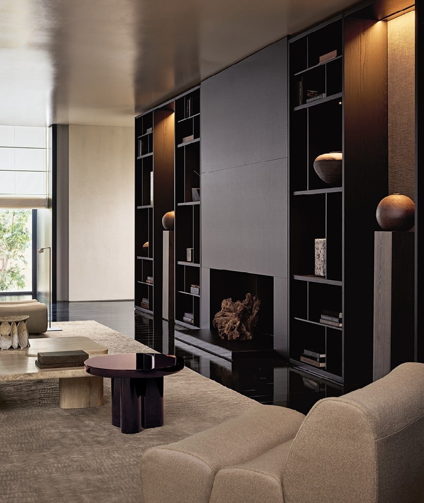 Surface wall panelling in fabric Mesh bronzo with mat ardesia profiles. Wall System composition with structure and recessed shelves in black elm, grids and backs in metal lacquer bronzo, compartments with Stage backs in fabric Mesh moka, integrated led light. Carpet Trace white.