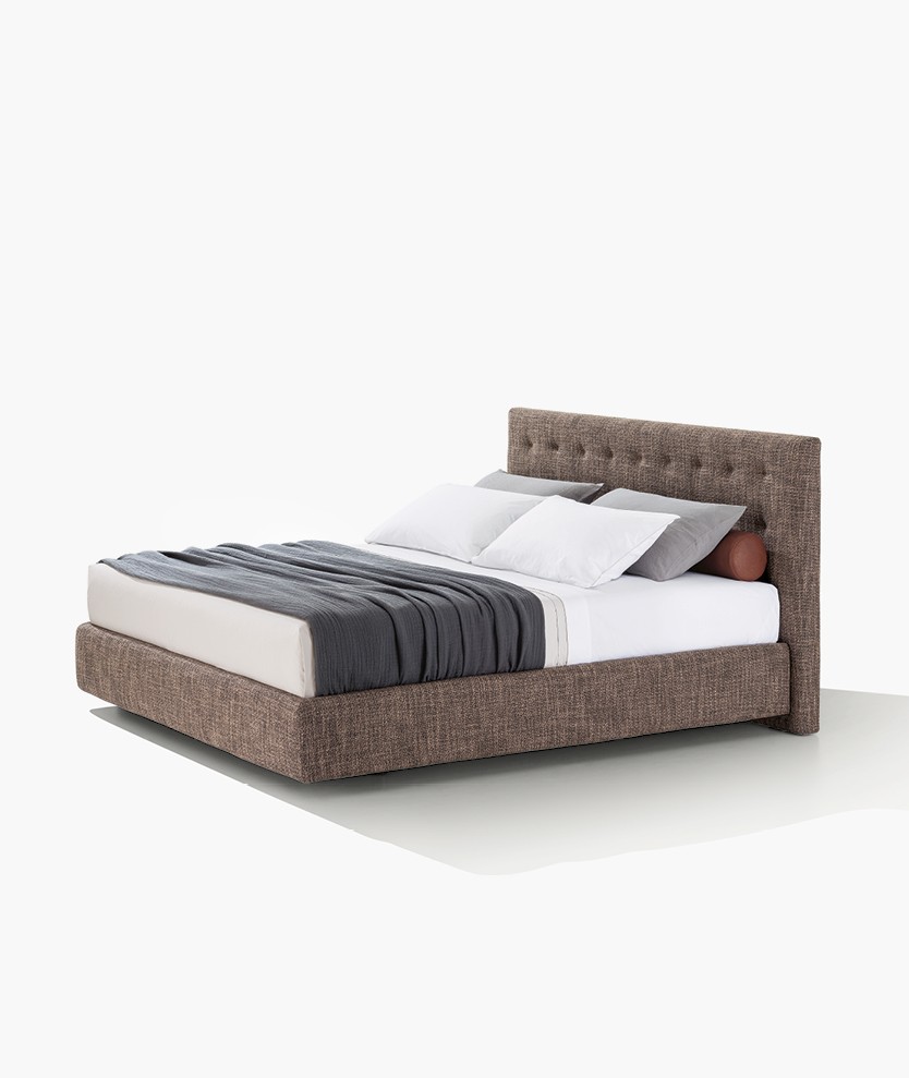 Arca bed with quilted padded headboard, removable covering in fabric Antea 05 terra di siena. Roll cushions in removable leather Silk 10 terracotta. Coordinated bed linen in cotton Provence 01 bianco with profile in polvere and 08 polvere with profile in bianco.