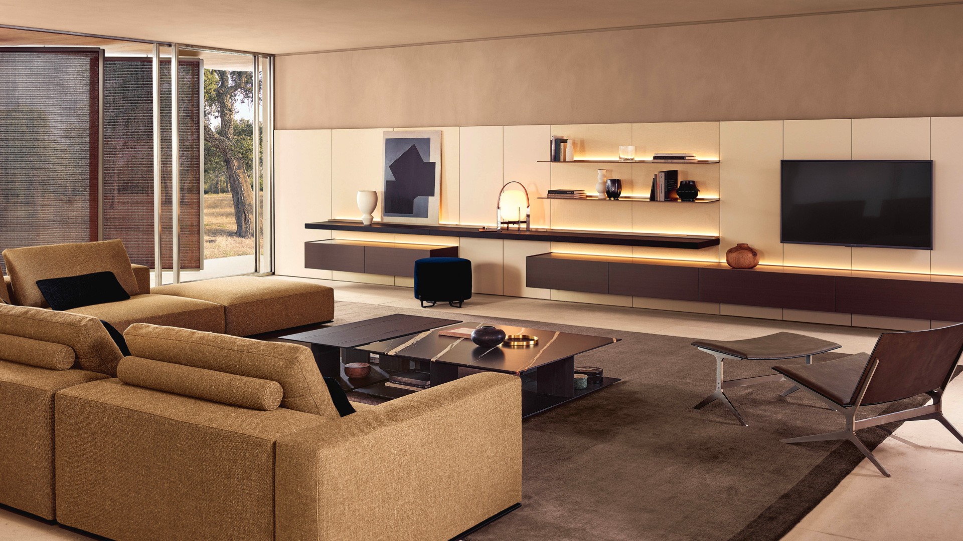 Декоративные панели Code с покрытием из текстиля цвета светлого льна. Профили с матовой отделкой цвета ардезия. Нижняя полка с подсветкой из черного вяза, канал с кабельными вводами из черного вяза с профилями с матовой отделкой цвета ардезия. Навесной корпусный модуль с задней подсветкой и с лакированной металлической отделкой под латунь. Верх из шлифованного мрамора Зечево и открытый отсек с лакированной матовой отделкой под латунь. Верхняя полка с лакированной металлической отделкой под латунь и встроенной светодиодной подсветкой. Шкаф Senzafine Cover с распашными дверями из травленого стекла цвета бронза и профилями с матовой отделкой цвета ардезия. Ручки Fitted с матовой отделкой цвета ардезия. Боковые стенки с лакированной металлической отделкой под латунь. Зеркало Circle с рамой из состаренной кожи (26) и зеркалом белого цвета. Стул Guest, несъемный чехол из кожи Tebe цвета нотте (08). Подушка сиденья со съемным чехлом с той же отделкой. Кушетка Bellport со съемным чехлом из ткани Arcadia цвета бронза (05), подушкой-валиком с ремешком из кожи черного цвета (02). Ножки с никелированной матовой отделкой Brown Nickel. Ковер Plain цвета тортора.