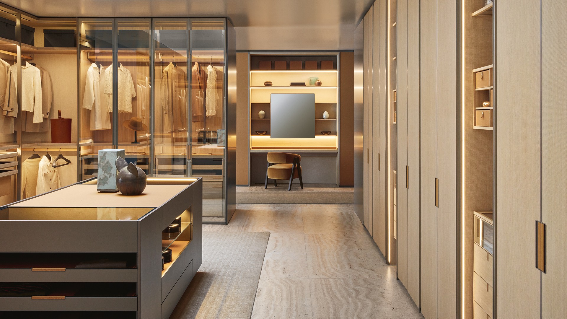 Гардеробная Senzafine из облагороженной плиты ореха blond с боковыми стенками рамы с матовой отделкой цвета champagne; задние части из ткани Mesh écru; боковые части с лакированной металлической отделкой цвета basalto. Оборудование Senzafine Suite, полки из облагороженной плиты ореха blond, сверхпрозрачное стекло с рамой с матовой отделкой цвета champagne, встроенная светодиодная подсветка. Штанги для вешалок с покрытием Tecnocover Grain 10 miele и матовой отделкой цвета champagne. Подставки из облагороженной плиты ореха blond с дном с покрытием Tecnocover Grain 10 miele и перегородкой из облагороженной плиты ореха blond, корзины с покрытием Tecnocover Grain 10 miele и рама из облагороженной плиты ореха blond. Шкаф Senzafine Swing с распашными дверями из прозрачного светоотражающего стекла и рамой с матовой отделкой цвета champagne, ручка Swing (может быть дополнена замком) с покрытием Tecnocover Grain 10 miele и с матовой отделкой цвета champagne; внутренняя часть из облагороженной плиты ореха blond, боковая часть рамы с матовой отделкой цвета champagne, оборудование Senzafine Suite. Остров в виде комода Set Up с лакированной металлической отделкой цвета basalto, верхняя столешница из дымчатого стекла и с покрытием Tecnocover Grain 10 miele, ящики и подставки с ручками с покрытием Tecnocover Grain 10 miele и матовой отделкой цвета basalto, дно с покрытием Tecnocover Grain 10 miele; открытые отделения с полкой из дымчатого стекла. Ковер Shindo natural.
