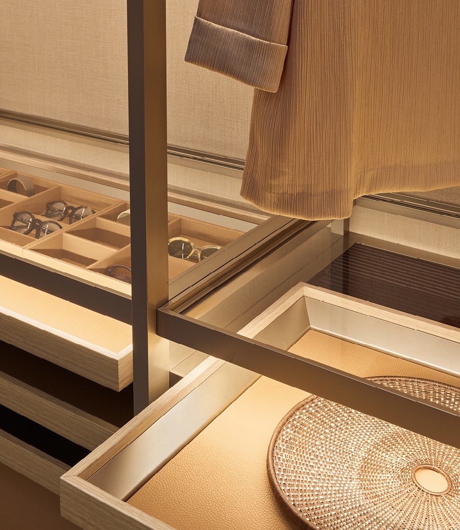 Крупный план: подставка из облагороженной плиты ореха blond с дном с покрытием Tecnocover Grain 10 miele, на задней части подставки есть горизонтальная шторка, закрывающая пространство, из которого достают подставку.